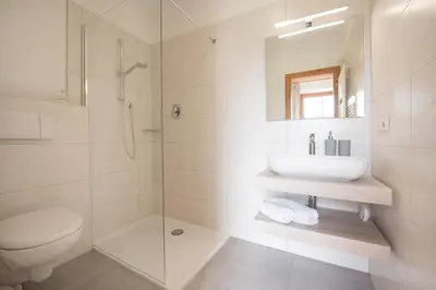 a white bathroom with a sink and a shower at Göllerhof in Caldaro
