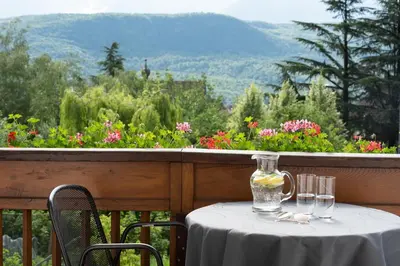 a table with wine glasses and a vase on a balcony at Göllerhof in Caldaro