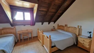 a bedroom with two beds and a table and a window at Malga Arpaco- camere e ristorante in Cinte Tesino