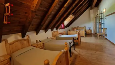 a bedroom with four beds in a room with wooden ceilings at Malga Arpaco- camere e ristorante in Cinte Tesino