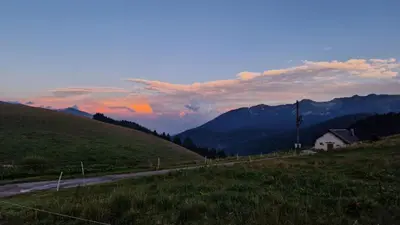 a road in the middle of a field with mountains at Malga Arpaco- camere e ristorante in Cinte Tesino