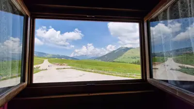 a window with a view of a road and mountains at Malga Arpaco- camere e ristorante in Cinte Tesino
