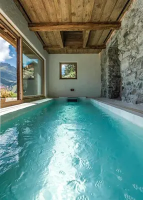 an indoor swimming pool with a wooden ceiling at Chalet Dolomites Luxe con Spa, Piscine, Jacuzzi e Cinema Privato in Livinallongo del Col di Lana