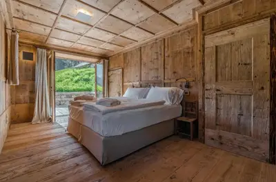 a bedroom with a bed in a room with wooden walls at Chalet Dolomites Luxe con Spa, Piscine, Jacuzzi e Cinema Privato in Livinallongo del Col di Lana