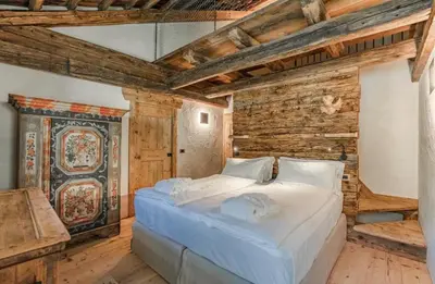 a bedroom with a large bed in a room with wooden walls at Chalet Dolomites Luxe con Spa, Piscine, Jacuzzi e Cinema Privato in Livinallongo del Col di Lana