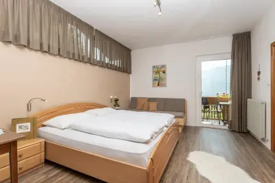 a bedroom with a large bed and a balcony at Sonnenhof- Urlaub auf den Bauernhof in Montagna
