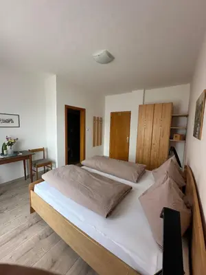a bedroom with a large bed with white sheets at Sonnenhof- Urlaub auf den Bauernhof in Montagna
