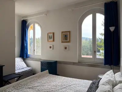 a bedroom with two windows and a bed and a couch at Dimora al Penegal, Passo Mendola Ospitar in Mendola