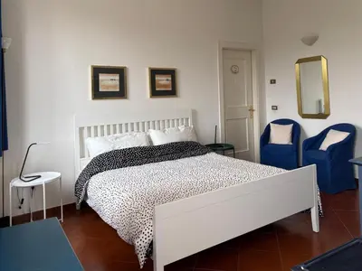 a bedroom with a white bed and two blue chairs at Dimora al Penegal, Passo Mendola Ospitar in Mendola