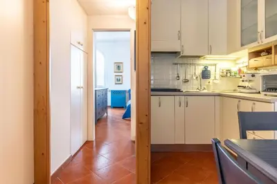 a kitchen with white cabinets and a wooden floor at Dimora al Penegal, Passo Mendola Ospitar in Mendola