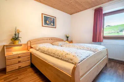 a bedroom with a wooden bed and a window at Kreuzerhof in Siusi