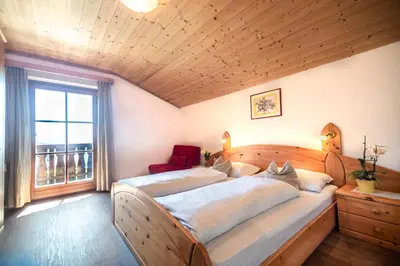 a bedroom with a large wooden bed with a window at Kreuzerhof in Siusi
