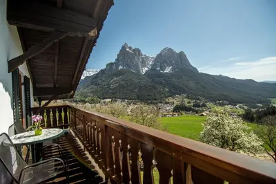 a balcony with a table and mountains in the background at Kreuzerhof in Siusi