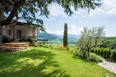 a garden with picnic tables and a view of mountains at Villa Barleit in Caldaro