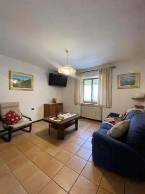 a living room with a blue couch and a table at Appartamento Madama in Falcade
