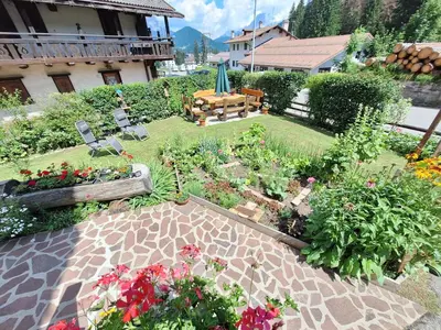 a garden with flowers and a table and chairs at Appartamento Madama in Falcade