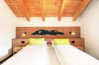 a bedroom with two beds and a wooden wall at Residence Odlina in Colfosco