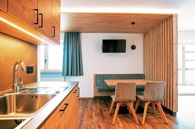 a kitchen with a wooden table and two chairs at Residence Odlina in Colfosco