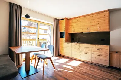 a living room with a table and a kitchen at Residence Odlina in Colfosco