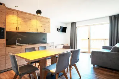 a kitchen and dining room with a wooden table and chairs at Residence Odlina in Colfosco
