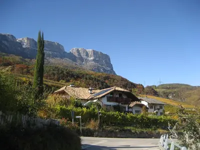 a house on a hill with mountains in the background at Gfillhof Ferienwohnung 3 in Eppan an der Weinstrasse ST. Pauls