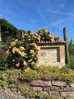 a sign with flowers on top of a stone wall at Gfillhof Ferienwohnung 3 in Eppan an der Weinstrasse ST. Pauls