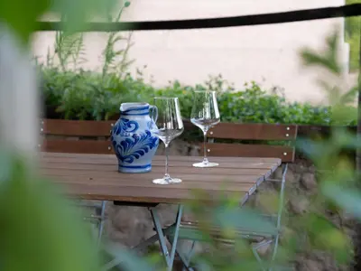 two wine glasses and a blue and white vase on a wooden table at Eden Apartment in Soprabolzano