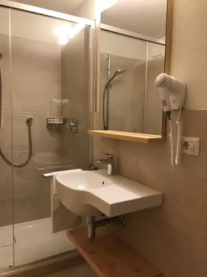 a bathroom with a sink and a shower and a phone at Platzerhof in Monguelfo