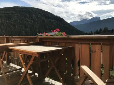 a wooden table on a deck with a view of mountains at Platzerhof in Monguelfo