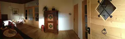 a living room with a wooden floor and a room with a grandfather clock at Platzerhof in Monguelfo