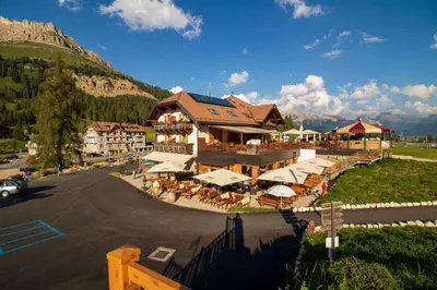 a building with tables and chairs in front of a mountain at Bar-Restaurant-Pizzeria Antermont B&B in Carezza al Lago