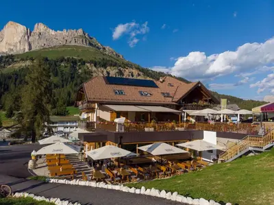 a building with tables and chairs and a mountain at Bar-Restaurant-Pizzeria Antermont B&B in Carezza al Lago