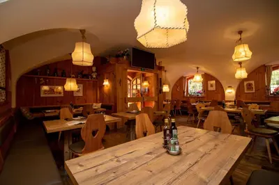 a restaurant with wooden tables and chairs and lights at Bar-Restaurant-Pizzeria Antermont B&B in Carezza al Lago