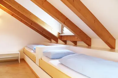 two beds in a attic room with wooden ceilings at Manzoni Rooms in Merano