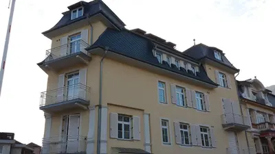 a yellow building with a black roof at Manzoni Rooms in Merano