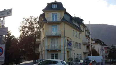 a yellow building with cars parked in front of it at Manzoni Rooms in Merano