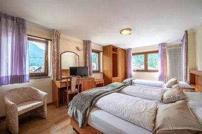 a hotel in the mountains with a grass field at De Matie in Canazei