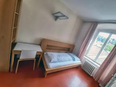 a bedroom with a bed and a table and a window at Priesterseminar Brixen in Bressanone
