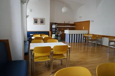 a classroom with tables and chairs and a kitchen at Priesterseminar Brixen in Bressanone
