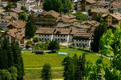 a view of a village with houses and a green field at Appartamento Larsech in Pozza di Fassa