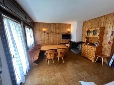 a dining room with a wooden table and a stove at Appartamento Larsech in Pozza di Fassa