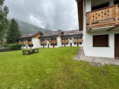 a building with a green lawn in front of it at Appartamento Larsech in Pozza di Fassa