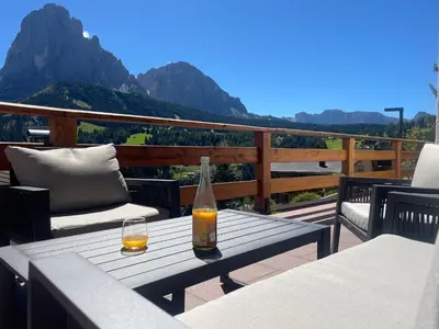 a bottle of drink on a table on a balcony at La Funtana in Santa Cristina in Val Gardena