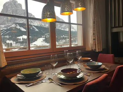 a table with plates and wine glasses and a mountain view at La Funtana in Santa Cristina in Val Gardena