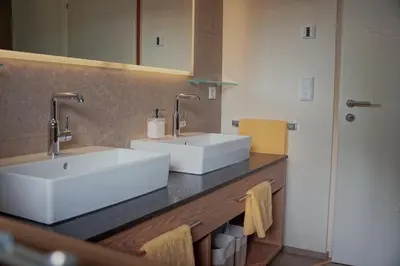 a bathroom with two white sinks on a counter at Monte Sole Suite - mit Sauna & Garten in Perca