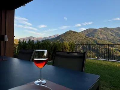 a glass of wine sitting on a table with a view at Monte Sole Suite - mit Sauna & Garten in Perca