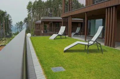 two chairs sitting on the grass next to a building at Monte Sole Suite - mit Sauna & Garten in Perca