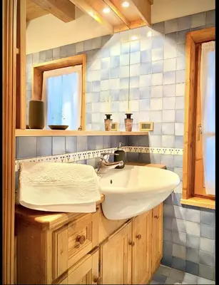 a bathroom with a white sink and blue tiles at Appartamento ampezzano con ampia balconata in San Vito di Cadore