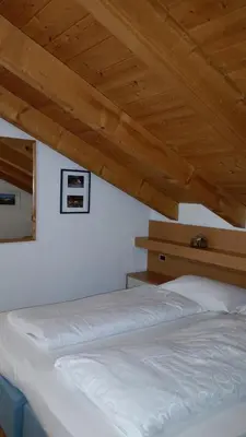 two beds in a room with wooden ceilings at Chalet Karin in Arabba