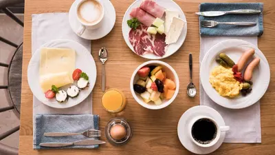 a wooden table topped with plates of food and coffee at Flora Hotel & Suites in Merano